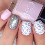 A person holding a pink and silver manicure with animal print nail art
