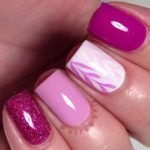 A person holding a pink and purple manicure with nail art designs for short nails