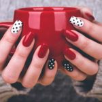 Quinceanera image: A woman holding a red cup with polka dots on it and displaying nail art with mini balls design