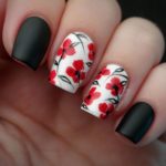 Quinceanera themed nail art, a person holding a black and white manicure with red flower designs