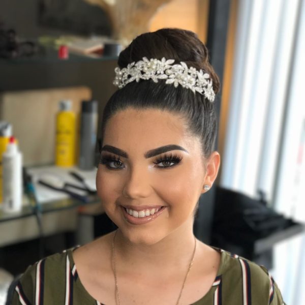 A smiling woman with long hair wearing a headband in a Quinceanera hair salon