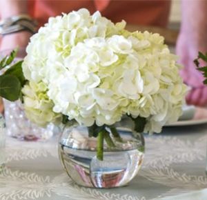 Quinceanera table decoration with a vase of white hydrangea flowers