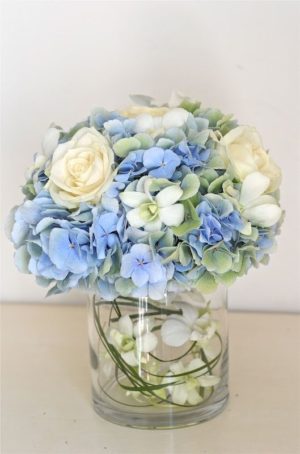 Quinceanera table centerpiece with blue and white hydrangea flowers in a vase