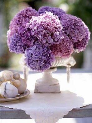 Quinceanera image: A beautiful floral arrangement with purple hydrangeas, displayed in a vase on a table.