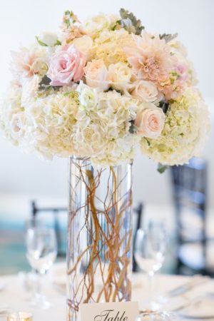 An elegant Quinceanera centerpiece table featuring a vase filled with white and pink hydrangea flowers.