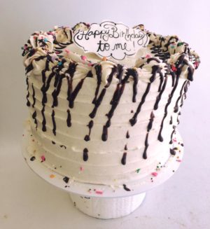 A Quinceanera cake featuring a buttercream design with white icing, chocolate icing, and sprinkles