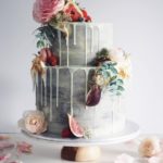 Quinceanera cake, a three tiered cake with flowers and figs on top of it