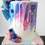 A Quinceanera birthday cake with a drip cake design and colorful icing on top, resembling a cupcake