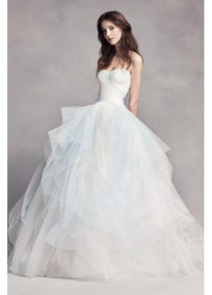 A woman in a Quinceanera dress posing for a picture, wearing a white Quinceanera dress designed by Vera Wang