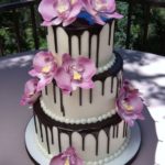 A three-tiered Quinceanera cake with purple flowers on top, decorated