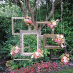 A picture frame hanging from a tree in a garden, showcasing summer outdoor Quinceanera decoration ideas.