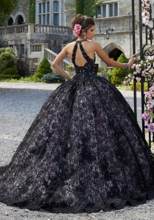 A woman in a black dress standing in front of a gate, wearing gown Quinceañera dresses.