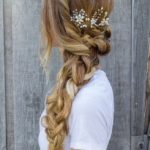 A woman with long blonde hair and a flower in her hair, wearing a Quinceanera dress and a comb in her hair