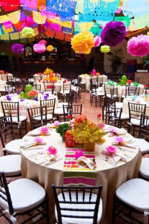 Quinceanera, a room filled with lots of tables covered in paper flowers, Mexican wedding decoration ideas