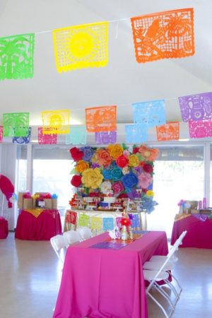 A table in a room filled with lots of colorful decorations for a Quinceanera celebration.