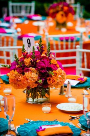 Quinceanera party with Mexican decorations. The table is set up with orange and pink flowers.