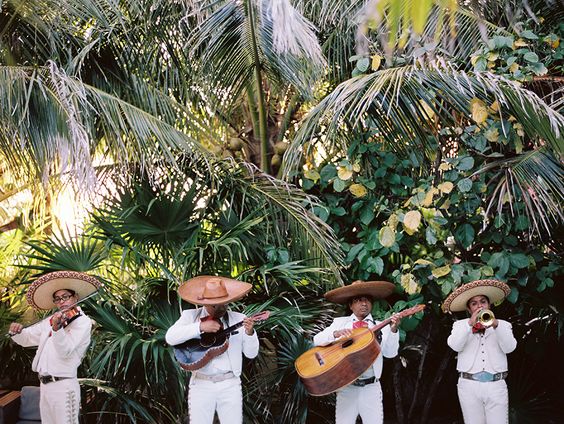A group of men in white suits playing instruments at a Quinceanera celebration