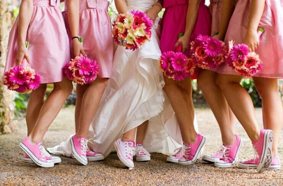 A quinceanera and her court of honor pose for a picture in their long dresses and converse shoes