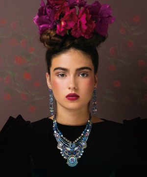 A traditional Quinceanera image featuring Frida Kahlo, a woman in a black dress with flowers on her head, wearing traditional Hispanic makeup.