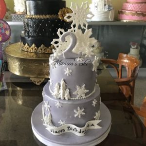 A Quinceanera cake, featuring a three-tiered design adorned with snowflakes on top, displayed at Tha Phae Gate.