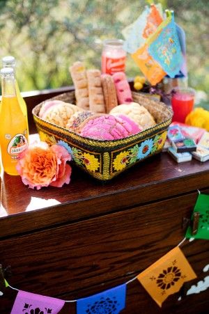 A wooden table topped with a bowl of food and drinks, as a gift basket for a Quinceañera celebration.