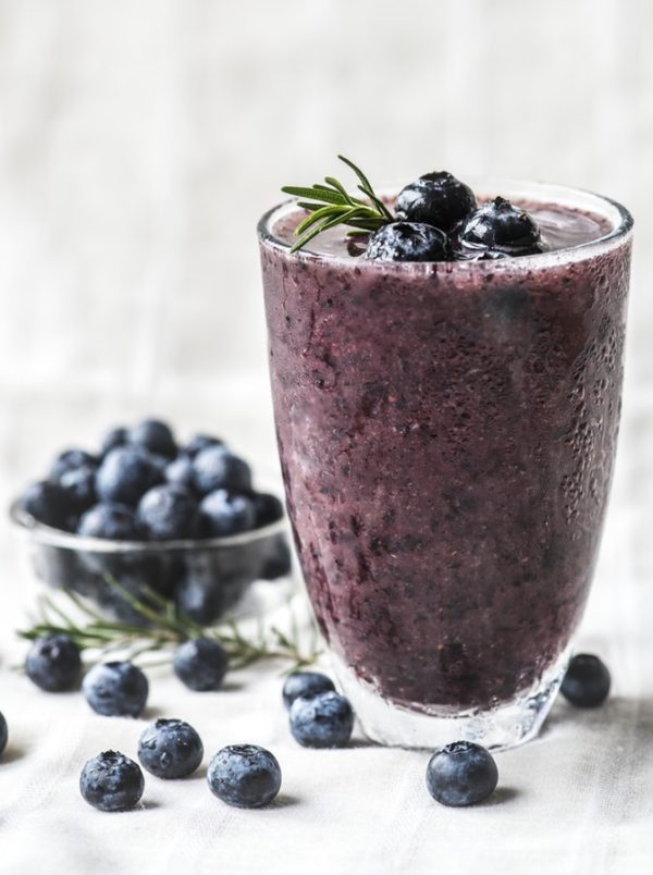 A Quinceanera themed image featuring a glass of blueberry smoothie topped with a sprig of rosemary