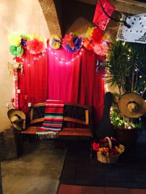 Quinceanera party in a room decorated with Mexican photo booth ideas, featuring decorations and a bench