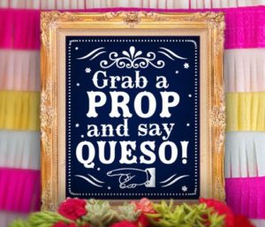 A Quinceanera themed image with a sign that says 'grab a prop and say queso' surrounded by paper props.