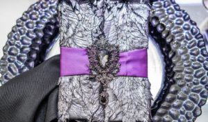 A lavender colored Quinceanera dress with a purple ribbon tied to a black and white jacket.