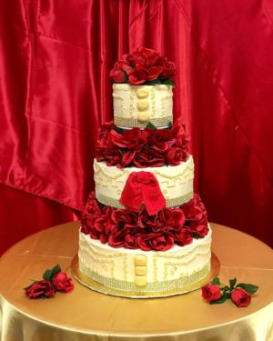 A three-tiered Quinceanera cake with red roses designed in a charro theme