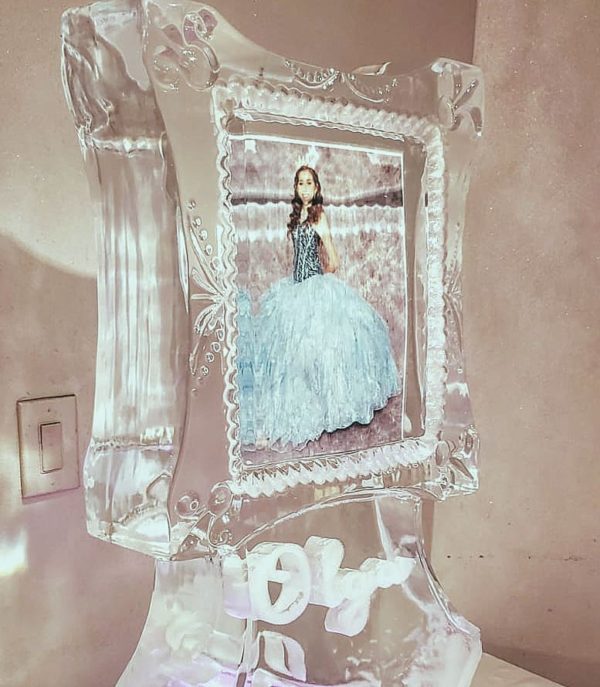 A Quinceanera gown with an ice sculpture and a doll in a glass frame