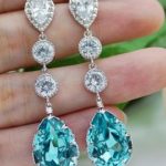 Quinceanera: A person holding a pair of blue and white earrings