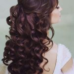 Quinceanera: A woman with long brown hair wearing a white dress in a bounce hairstyle