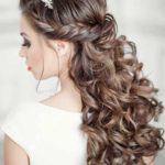A woman with long hair and a flower in her hair, showcasing a sweet sixteen hairstyle for a Quinceanera