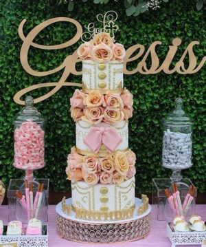 Quinceanera Charro Cake - A three-tiered pink and gold cake with Quinceanera decorations
