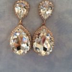 A pair of gold colored earrings sitting on top of a table for a Quinceanera