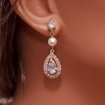 A close up of a person wearing a pair of rose gold Quinceanera earrings