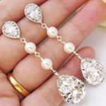 A person holding a pair of Quinceanera earrings in their hand