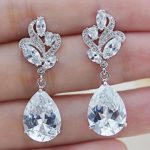 A person holding a pair of Quinceanera earrings in their hand