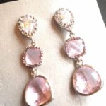 A pair of pink and white Quinceanera earrings sitting on top of a table