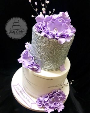 A Quinceanera cake, a three tiered cake with purple flowers on top, decorated for the special occasion