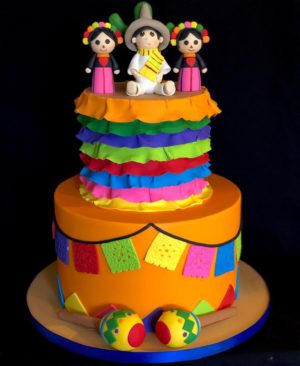 A Mexican doll cake with sugar decorations on top, consisting of three tiers.