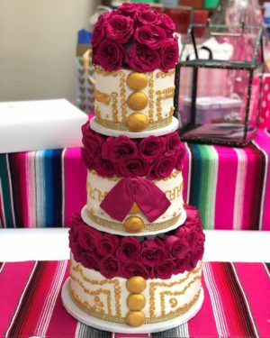 A Quinceañera charro themed centerpiece consisting of a three-tiered cake adorned with red flowers on top