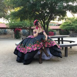 A woman in a costume Quinceañera dress sitting on a bench