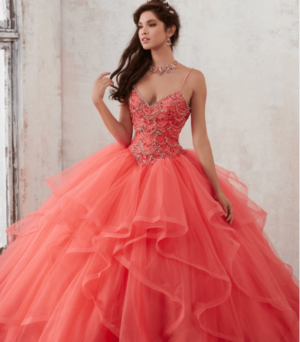 A woman in a coral pink dress posing for a picture at a Quinceanera event, alongside a Quinceañera dress creation