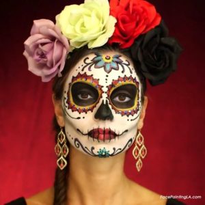 Quinceanera image description: Day of the Dead, a woman wearing a sugar skull makeup with roses in her hair