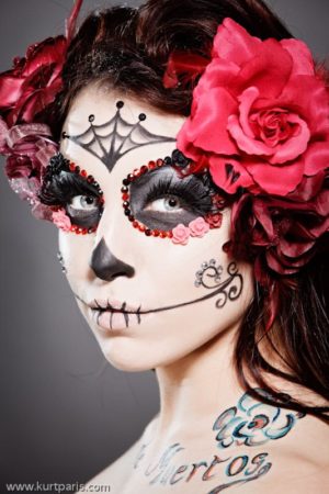 A Quinceanera woman wearing Dia de los Muertos face paint with a rose in her hair