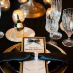 Table set for a Quinceanera celebration with a black and gold place setting in a Gatsby theme