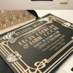 A black and gold Quinceañera invitation book sitting on top of a table