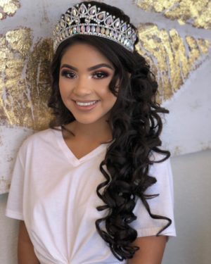 Quinceanera: A woman with long hair wearing a tiara and posing for a picture